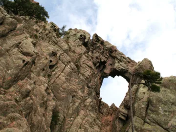 L'arche rocheuse percée du Trou de la Bombe dans une paroi de granit du massif de Bavella, vue d'en bas