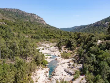 Vasques d'eau verte entre des dalles de granit clair dans la vallée boisée du Cavu, vues du ciel