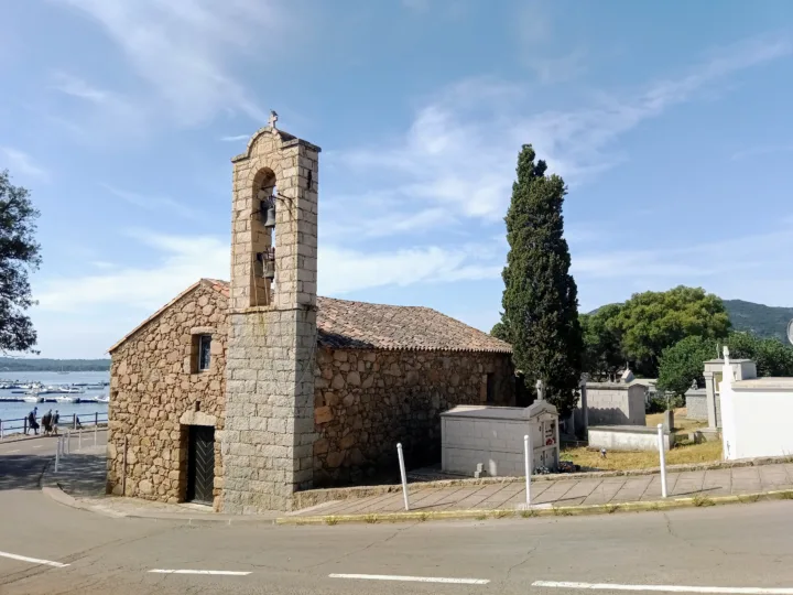 Chapelle Saint-Joseph en granit avec son clocher, à l'entrée de Pinarello, tombes du cimetière marin et golfe en arrière-plan