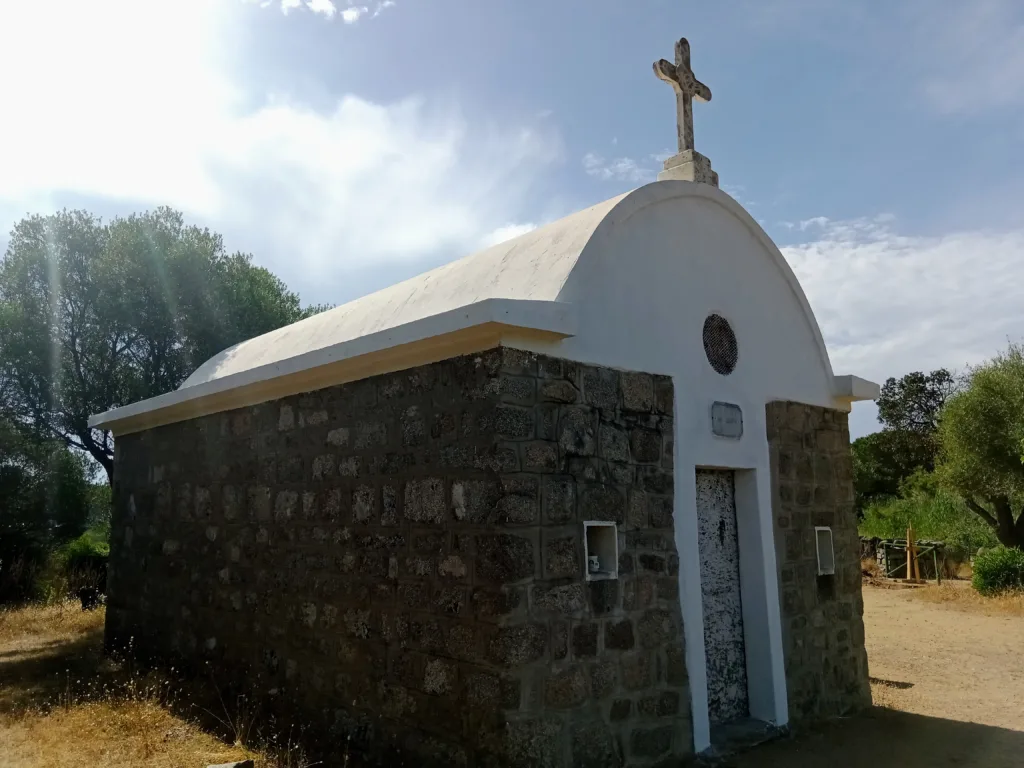 Petite chapelle Sainte-Barbe en pierre, toit arrondi blanc surmonté d'une croix, entourée de maquis