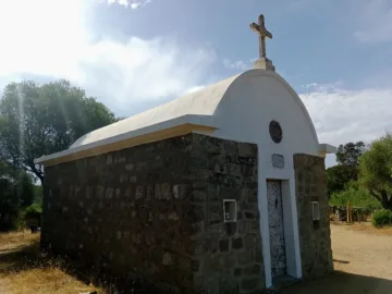 Petite chapelle Sainte-Barbe en pierre, toit arrondi blanc surmonté d'une croix, entourée de maquis