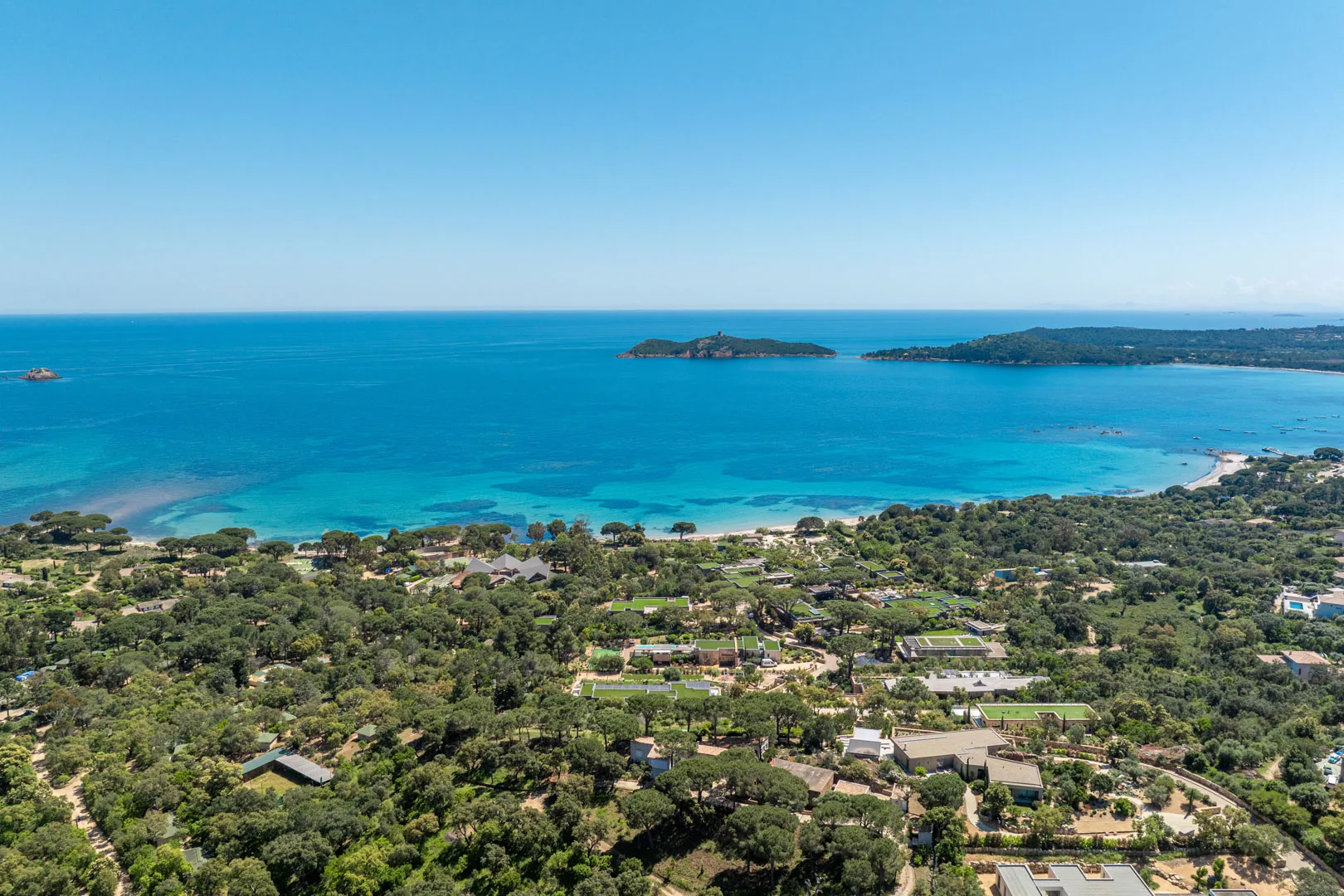 Vue aérienne du golfe de Pinarello : maquis et maisons au premier plan, îlot de la Ruscana, île de Pinarellu et sa tour au large