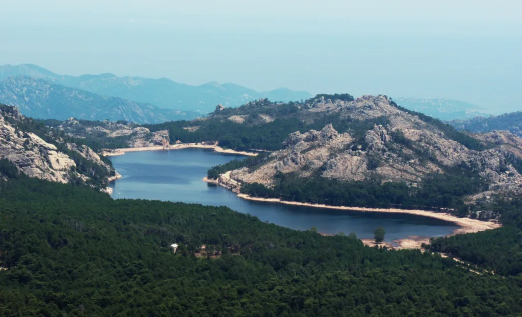 Le lac de l'Ospedale entouré de forêt et de reliefs granitiques, vu d'un sommet