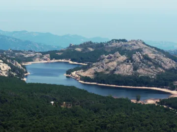 Le lac de l'Ospedale entouré de forêt et de reliefs granitiques, vu d'un sommet