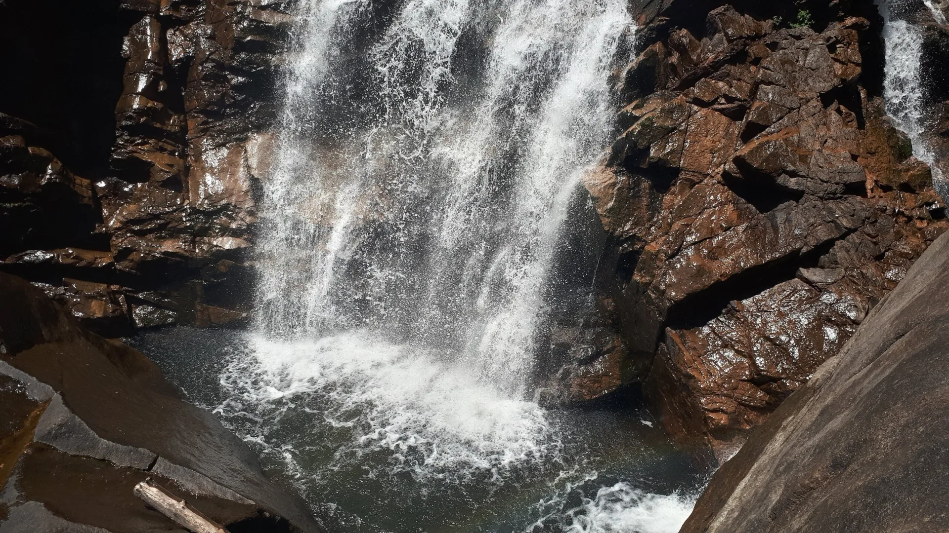 Chute d'eau de Piscia di Gallu tombant entre des parois de granit sombre dans un bassin