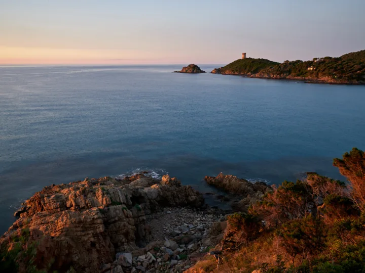 Lever du soleil sur la côte de Fautea, rochers de granit au premier plan et tour génoise sur son promontoire