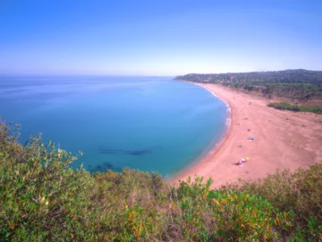 Longue plage courbe de sable du Lavu Santu bordée de maquis, vue depuis le sentier du littoral