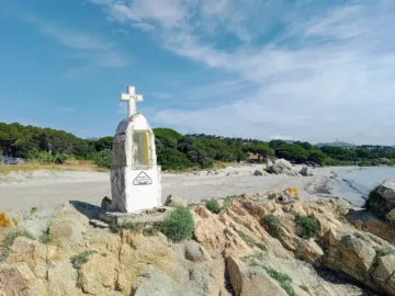 Oratoire blanc surmonté d'une croix sur les rochers, au bord de la plage de la Ruscana à Pinarello
