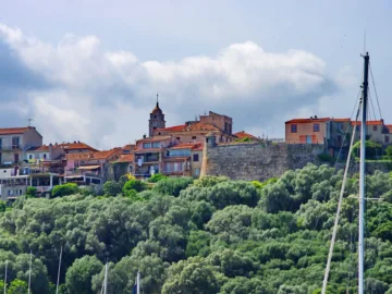 La vieille ville de Porto-Vecchio sur sa colline, maisons, clocher et murs de pierre au-dessus de la végétation