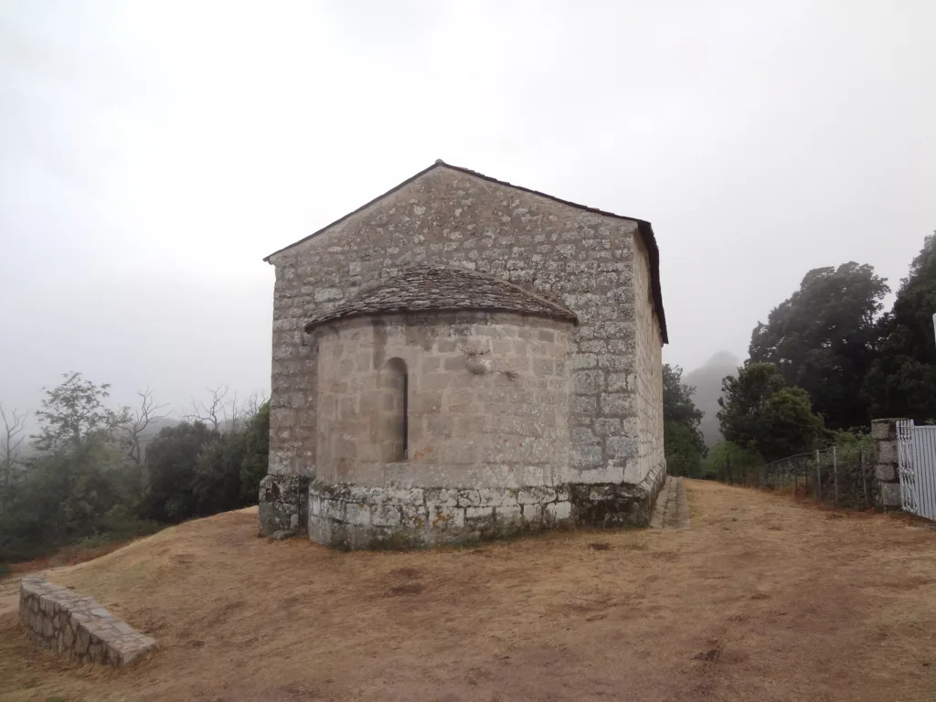 Chevet et abside en pierre de la chapelle romane Santa Maria de Quenza, dans la brume