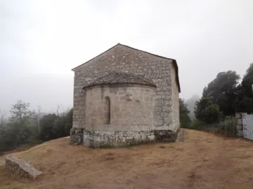 Chevet et abside en pierre de la chapelle romane Santa Maria de Quenza, dans la brume